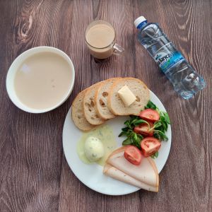 Zdjęcie przedstawia Dietę podstawową  Płatki jęczmienne na mleku Chleb mieszany pszenno-żytni Masło extra Jajko w sosie tatarskim Filet zapiekany drobiowy Pomidor Woda mineralna Kawa zbożowa z mlekiem Roszponka